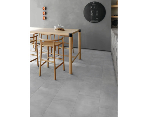 Heller Raum mit Esstisch und Stühlen auf grauem Fliesenboden.