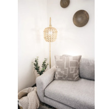 Helle Raumszene mit Sofa, Kissen mit geometrischem Muster und Stehlampe