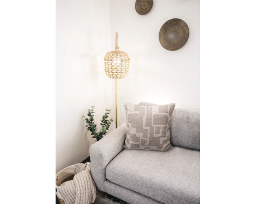 Helle Raumszene mit Sofa, Kissen mit geometrischem Muster und Stehlampe