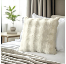 Coussin décoratif en fourrure sur un lit dans une chambre.
