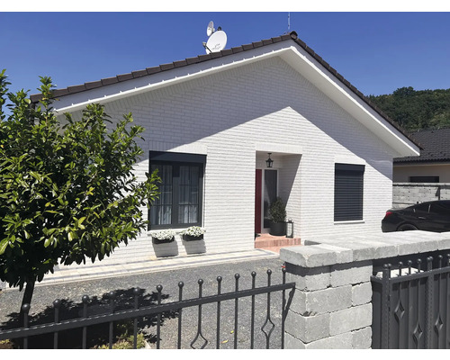 Einfamilienhaus mit weißen Ziegeln, grauen Fensterrahmen und Rollläden