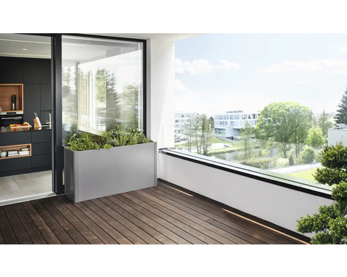 Szene mit einem bepflanzten, rechteckigen Pflanzkasten auf einem Balkon mit Holzboden.