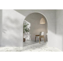 Vue à travers un arc dans une pièce avec des carreaux à motifs, une chaise, une suspension et une plante.