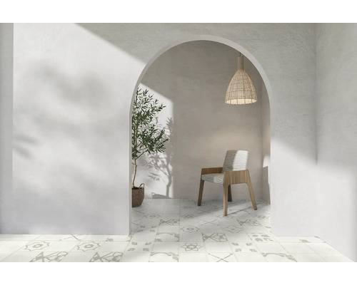 Vue à travers un arc dans une pièce avec des carreaux à motifs, une chaise, une suspension et une plante.