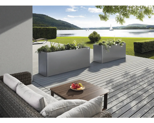 Terrasse mit Pflanzkästen und Sitzgruppe vor Seelandschaft