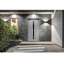 Moderne Haustür mit Glaseinsatz in einer Steinmauer mit Wegplatten