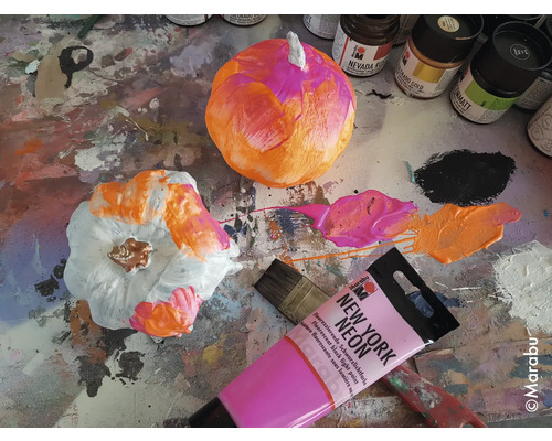 Citrouilles peintes avec de la peinture, un pinceau et des tubes de peinture sur une surface de travail.