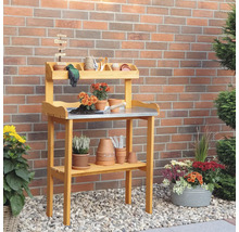 Table de jardin en bois avec étagères et accessoires de jardin devant un mur en briques