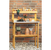 Table de jardin en bois avec accessoires de plantation et panneaux indicateurs devant un mur de briques