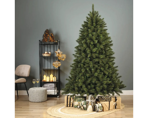 Sapin de Noël décoré avec des cadeaux sur un tapis tressé dans un salon.