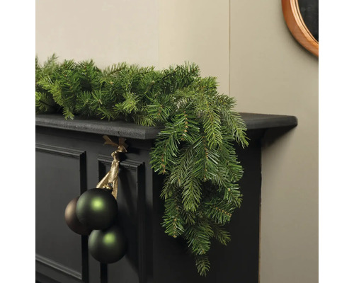 Dekorierter Kaminsims mit Tannengirlande und Weihnachtskugeln für festliche Atmosphäre