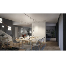 Salle à manger lumineuse avec table, chaises et luminaires suspendus sur un système de rails