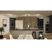 Cuisine moderne avec îlot central, table à manger et éclairage sur rail flexible.