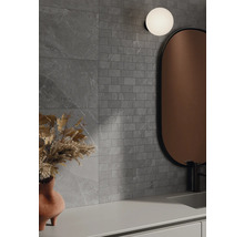 Badezimmer mit grauen Wandfliesen in Steinoptik, Spiegel und Lampe