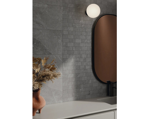 Badezimmer mit grauen Wandfliesen in Steinoptik, Spiegel und Lampe