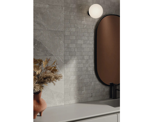 Salle de bains avec carreaux muraux gris aspect pierre, miroir et lampe