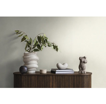 Scène décorative avec un vase à fleurs, des sculptures et des livres sur une armoire en bois sombre.