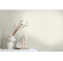 Scène décorative avec un vase, des branches, une bougie, une horloge et une sculpture sur une table.