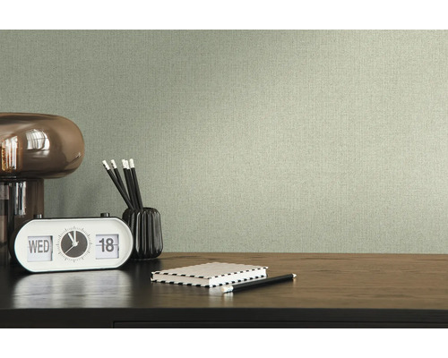 Textiltapete im Wohnraum mit Schreibtisch, Lampe, Uhr, Stiften und Notizbuch