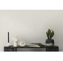 Décoration de salon sur une étagère avec bougies, sculpture, horloge, livres, bol et plante en pot devant un mur uni