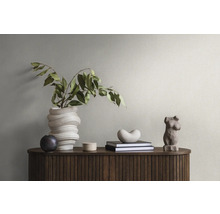 Éléments décoratifs sur une armoire en bois à structure rainurée : un vase torsadé avec des branches, une petite sphère, une boîte, des livres, une forme de cœur et une sculpture de torse féminin.