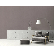 Salon avec fauteuil, lampe et objets de décoration sur une commode devant un mur à motifs