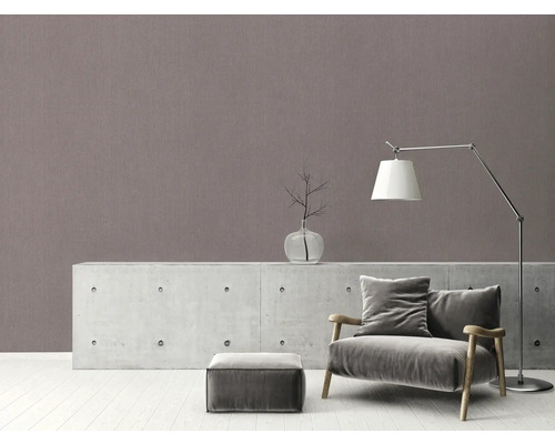 Wohnzimmer mit Sessel, Lampe und Dekorationsartikel auf Kommode vor gemusterter Wand