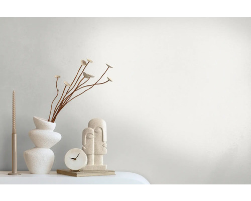 Dekorative Anordnung mit Vase, Pflanzen, Kerze, Uhr und Skulptur auf einem Tisch