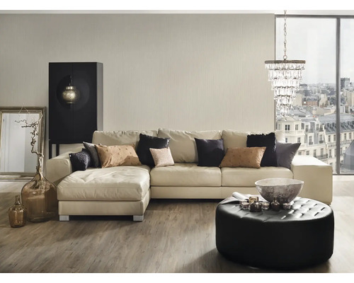 Wohnzimmer mit Ecksofa, Ottoman, Couchtisch und Dekorationsgegenständen.