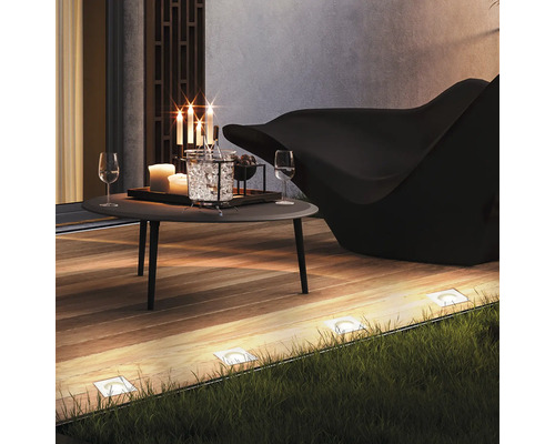 Terrassenszene mit Tisch, Stuhl, Bodenleuchten und Dekoration für den Außenbereich