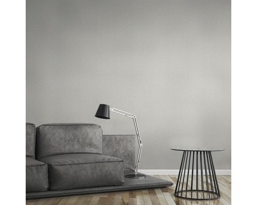 Graue Couchgarnitur mit Stehlampe und Beistelltisch vor einer strukturierten Wand