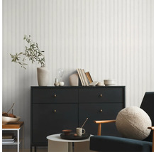 Salon moderne avec mur en lambris, commode, fauteuil et éléments décoratifs pour une ambiance élégante.