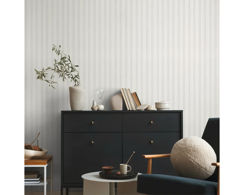 Modernes Wohnzimmer mit Paneelwand, Kommode, Sessel und dekorativen Elementen für ein stilvolles Ambiente.