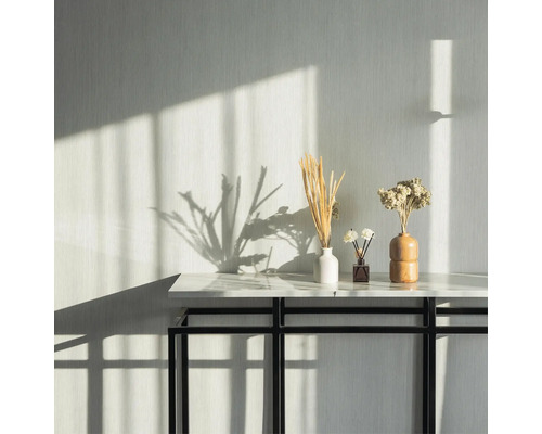 Table décorative avec vases de fleurs et diffuseur de parfum dans une pièce lumineuse.