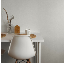 Szene mit einem Tisch, Stuhl, Tasse, Vase und Dekoration vor einer Wandtapete.