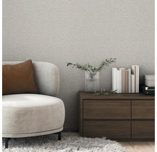 Salon avec fauteuil beige, commode et papier peint à motifs