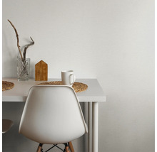 Scène avec table blanche, chaise, tasse et décoration devant un papier peint texturé