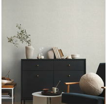 Wohnzimmer mit Textiltapete, Kommode und Sessel.