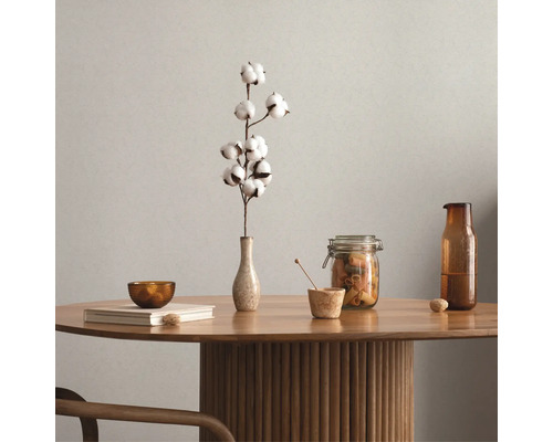 Arrangement décoratif sur une table en bois avec de la vaisselle et une fleur de coton dans un vase.