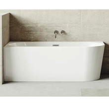 Rechteckige Badewanne aus Sanitäracryl mit Armaturen an einer Betonwand