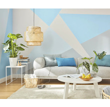 Wohnzimmer mit Sofa, Tisch, Pflanzen und geometrischer Wandgestaltung