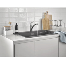 Küchenspüle mit Wasserhahn, Spülmittel, Geschirr und Schneidebrettern auf einer Küchentheke