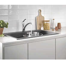 Küchenspüle mit Wasserhahn und Küchenutensilien auf der Arbeitsplatte.