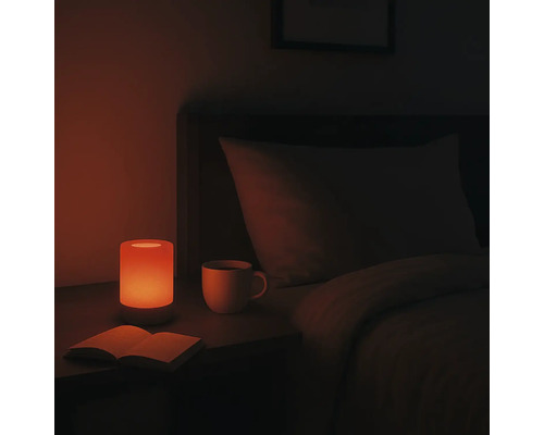 Table de chevet avec lampe, livre et tasse dans une chambre.