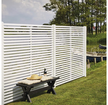 Éléments de clôture blancs avec des lamelles horizontales à côté d''un banc dans le jardin