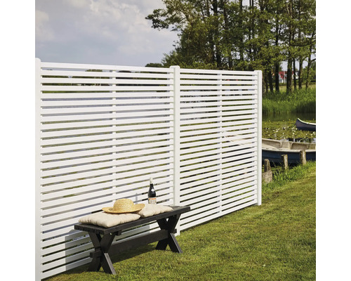 Éléments de clôture blancs avec des lamelles horizontales à côté d''un banc dans le jardin
