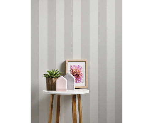 Intérieur décoratif avec papier peint rayé, table, plante, cadre photo et décoration.