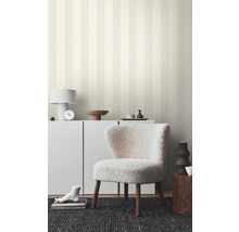 Espace de vie avec papier peint rayé, fauteuil et meubles blancs pour une ambiance lumineuse