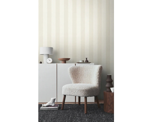 Espace de vie avec papier peint rayé, fauteuil et meubles blancs pour une ambiance lumineuse