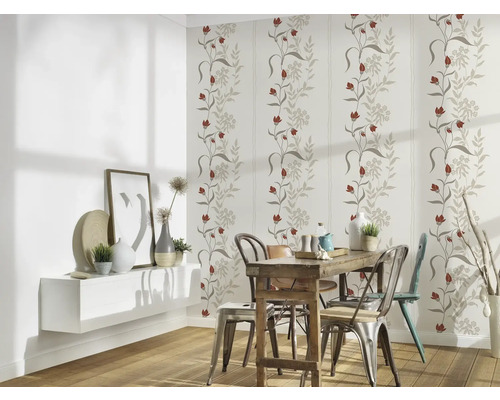 Salle à manger avec papier peint à motifs floraux, table en bois et chaises.
